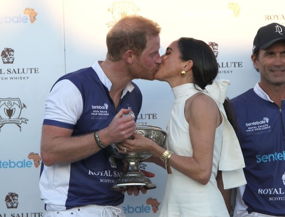 The Duchess of Sussex presents the trophy to her husband, the Duke of Sussex after his team the Royal Salute Sentebale Team defeated the Grand Champions Team, in the Royal Salute Polo Challenge, to be ...