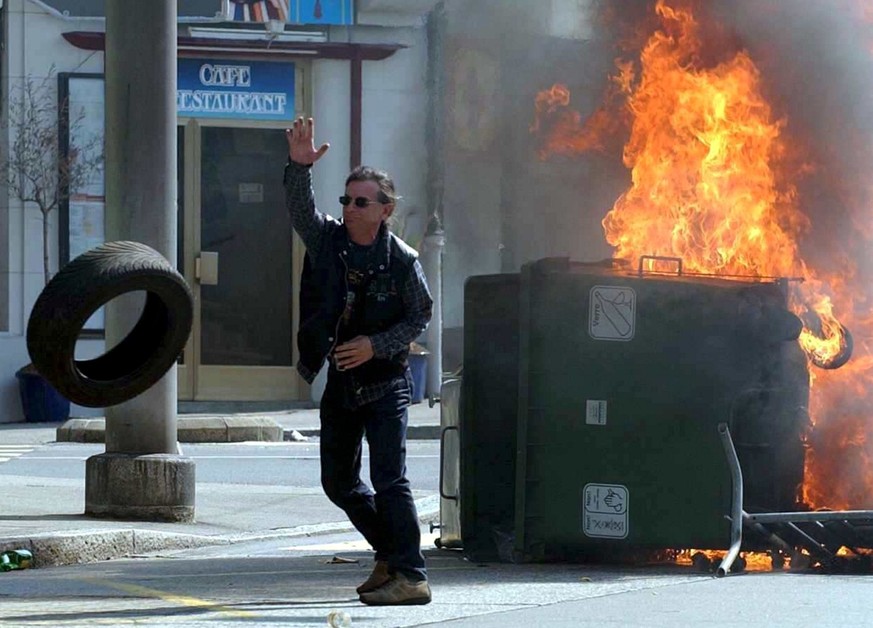 A demonstrator throws a car tire while in the back a trash can is burning, during an anti G8 demonstration in Lausanne, Switzerland, Sunday, June 1st, 2003. About 300 masked anti-globalisation activis ...