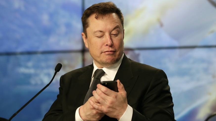 FILE - Elon Musk founder, CEO, and chief engineer/designer of SpaceX jokes with reporters as he pretends to search for an answer to a question on a cell phone during a news conference after a Falcon 9 ...