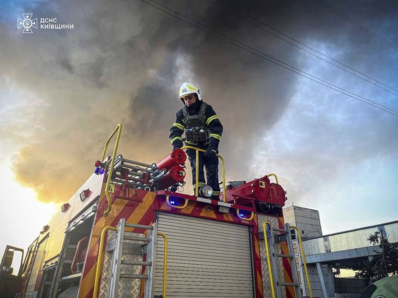In this photo provided by the Ukrainian Emergency Service, an emergency worker extinguishes a fire after a Russian attack on the Trypilska thermal power plant in Ukrainka, Kyiv region, Ukraine, Thursd ...