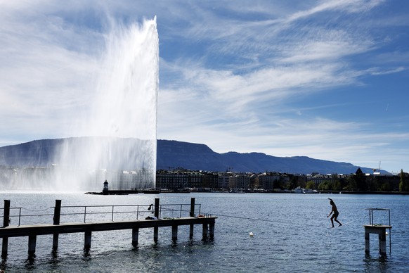 epaselect epa11262148 A man walking a slackline on a warm Spring day at Lake Geneva in front of the Geneva water fountain (Jet d'eau de Geneve) at the "Bains des Paquis" in Geneva, Swit ...