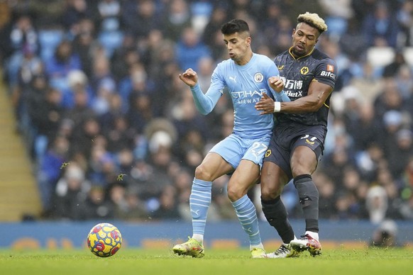 Manchester City's Joao Cancelo, left, challenges for the ball with Wolverhampton Wanderers' Adama Traore during the English Premier League soccer match between Manchester City and Wolverhamp ...