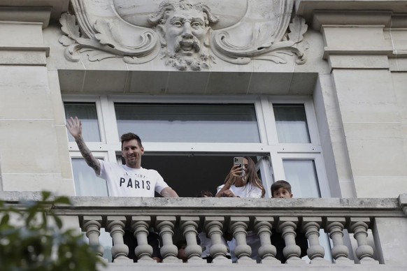 Argentinian soccer star Lionel Messi waves to supporters from his hotel balcony while his wife Antonella Roccuzzo takes photographs in Paris, Tuesday, Aug. 10, 2021. Lionel Messi finalized agreement o ...
