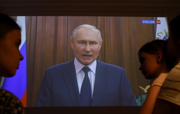 epa10712844 Members of a family watch Russian President Vladimir Putin&#039;s video address to the Nation on a tv screen, in Moscow, Russia, 26 June 2023. The Russian President on 26 June evening made ...