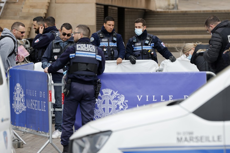 Police officers hide a dead body after a knife attack, outside the Marseille town hall, southern France, Saturday, March 12, 2022. A Frenchman with a knife injured three police officers in the souther ...