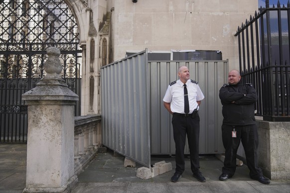 Security officials stand in front of large sheets of black plastic and two metal barriers which conceal street artist Banksy&#039;s latest artwork, a protester lying on the ground holding a blood-spla ...