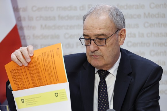 Bundesrat Guy Parmelin nimmt Dokumente aus einem Umschlag, waehrend einer Medienkonferenz des Bundesrates zum Lohnschutz, am Mittwoch, 19. Februar 2025, in Bern. (KEYSTONE/Peter Klaunzer)