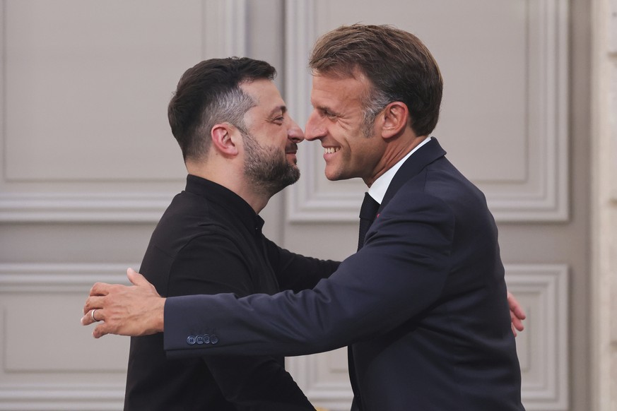France&#039;s President Emmanuel Macron, right, embraces Ukraine&#039;s President Volodymyr Zelenskyy at the end of a press conference following a summit on Ukraine at the Elysee Palace, in Paris, Fra ...