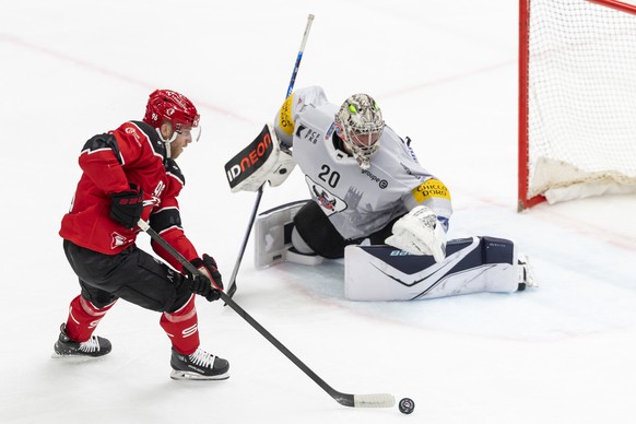 Drake Caggiula (LHC), gauche, lutte pour le puck avec le gardien Reto Berra (HCFG), droite, lors du match du championnat suisse de hockey sur glace de National League entre Lausanne HC, LHC, et HC Fri ...
