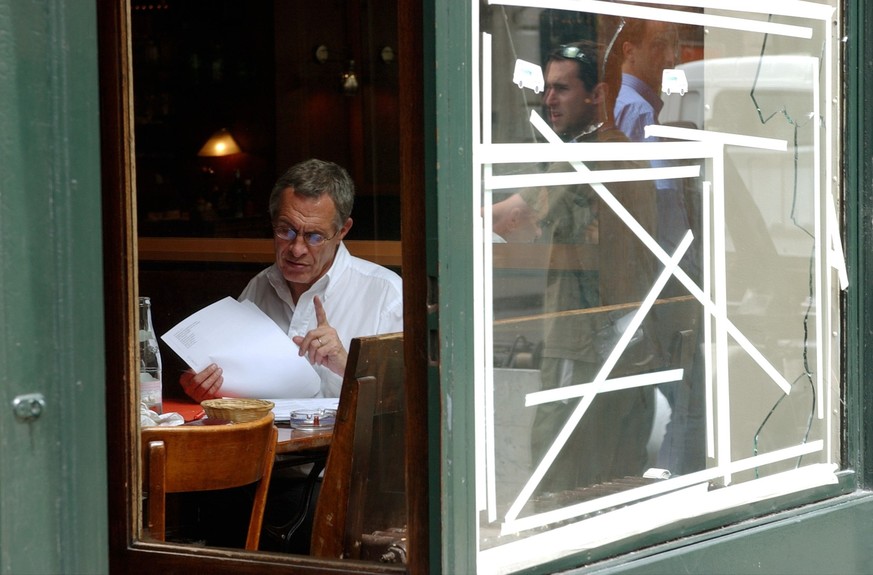 Une personne consulte des document dans un bistro de la rue du stand, avec des fenetres cassees, a Geneve 2. Juin 2003, apres trois jours des protests violents contre le sommet du G8 a Evian. (KEYSTON ...