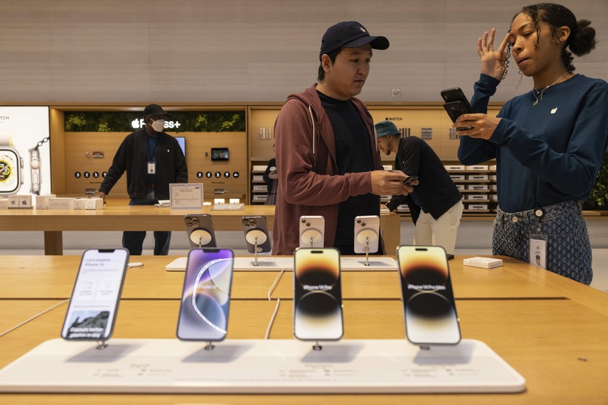 With iPhone 14 models in the foreground, an Apple employee talks with a customer at the Apple Fifth Avenue store, Friday, Sept. 16, 2022, in New York. (AP Photo/Yuki Iwamura)