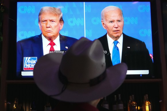Roger Strassburg, of Scottsdale, Ariz., wears a cowboy hat as he watches the presidential debate between President Joe Biden and Republican presidential candidate former President Donald Trump at a de ...