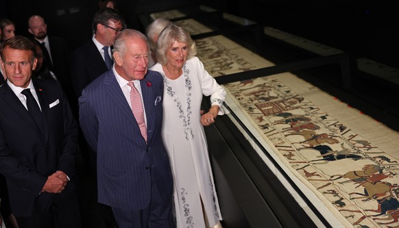 Britain's King Charles III, center, and France's President Emmanuel Macron, left, accompanied by their wives, Queen Camilla, right, and Brigitte Macron, obscured, view sections of the Bayeux ...