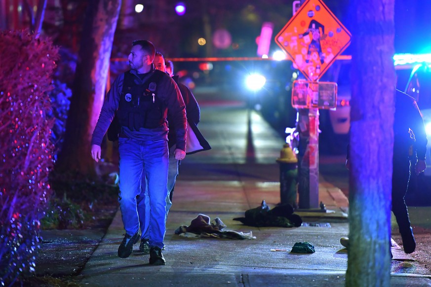 A law enforcement official walks past articles of clothing on a sidewalk near an entrance to Brown University, Saturday, Dec. 13, 2025, in Providence, R.I., during the investigation of a shooting. (AP ...