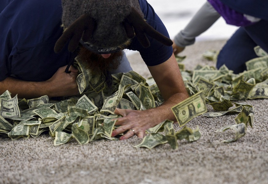 Patrick Heyen, Memorial Middle School teacher, shovels dollar bills into his shirt on Saturday, Dec. 11, 2021, in the first-ever Dash For Cash between periods at the Sioux Falls Stampede game in Sioux ...