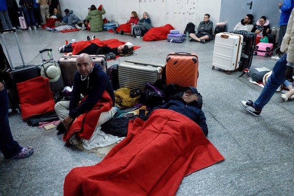Travelers covered with Red Cross blankets lie on the floor as they prepare to spend the night at the Atocha train station, following a massive power cut affecting the entire Iberian peninsula and the  ...