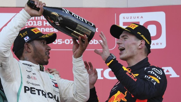 Race winner Mercedes driver Lewis Hamilton prepares to pour champagne on third placed Red Bull Racing driver Max Verstappen at left as they celebrate on the podium at the Japanese Formula One Grand Pr ...