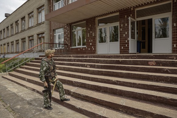 epa09978488 A militia man of the self-proclaimed Donetsk People&#039;s Republic guards the entrance of the school in Svitlodarsk, Donetsk region, Ukraine, 26 May 2022. Russia has taken control of the  ...