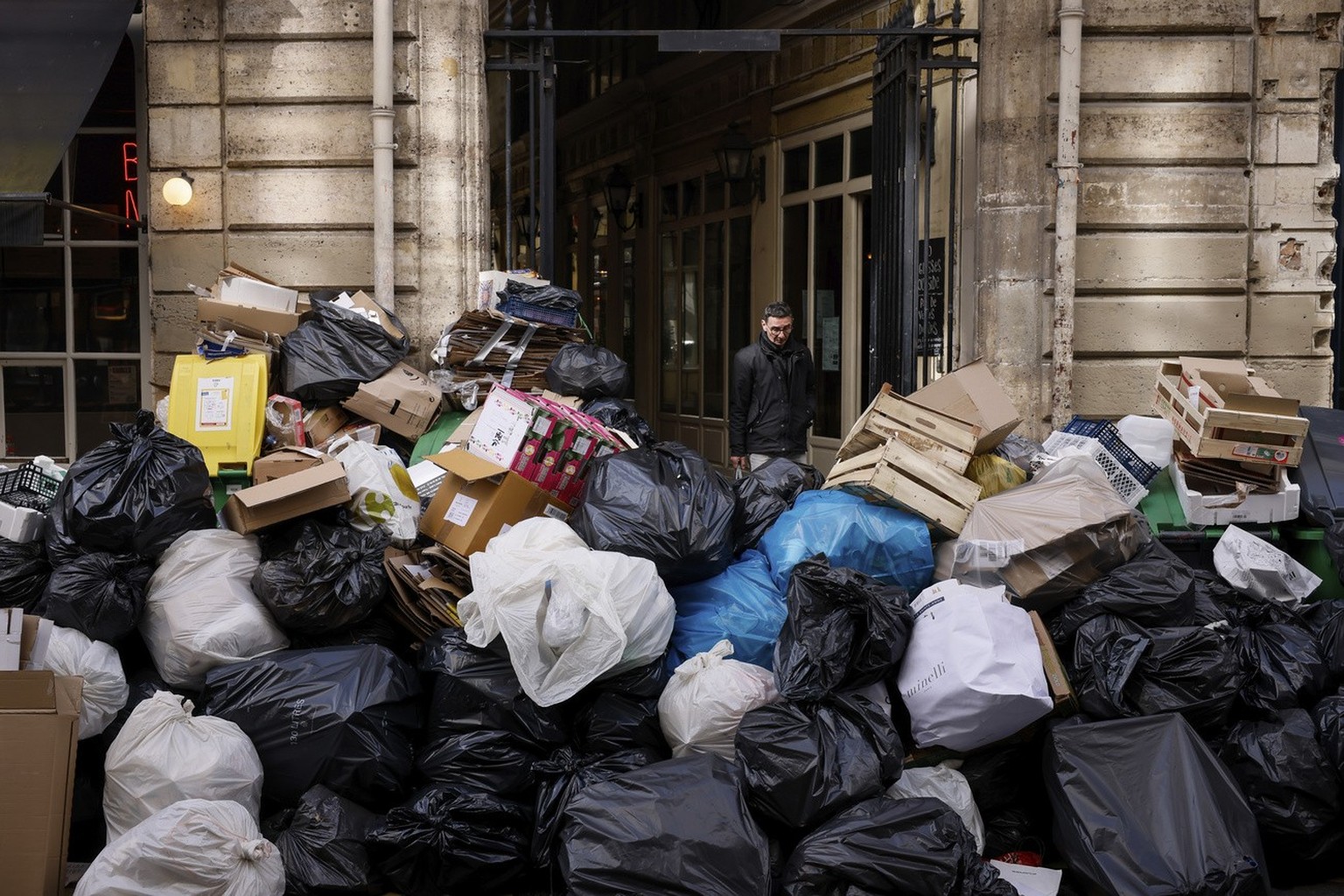 A man walks past uncollected garbages in Paris, Wednesday, March 15, 2023 as sanitation workers are on strike. Opponents of French President Emmanuel Macron&#039;s pension plan are staging a new round ...