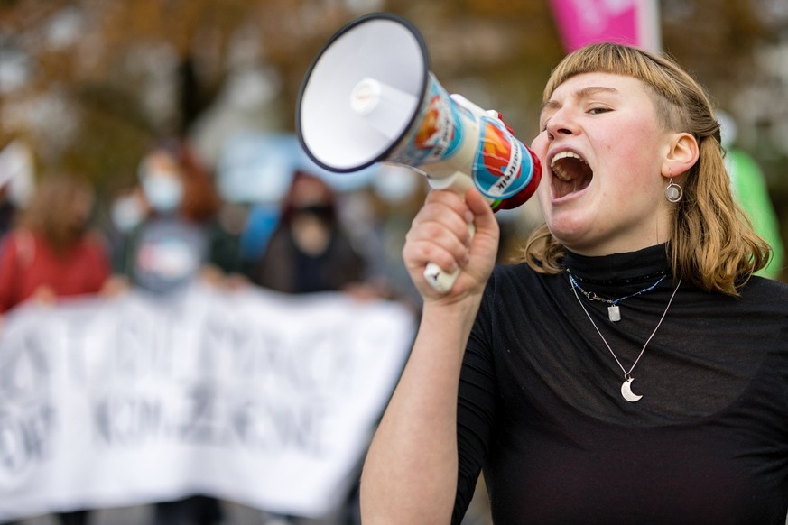 Eine Demonstrantin mit Megafon schreit bei einem Klimastreik gegen Grosskonzerne am Sonntag, 14. November 2021 in Zug. (KEYSTONE/Philipp Schmidli)