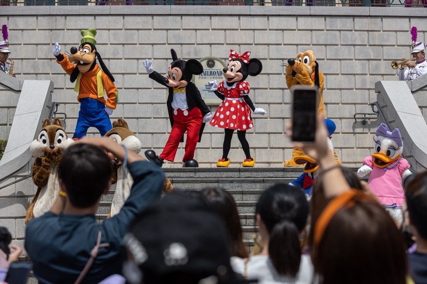 epa09902005 People watch a show featuring Disney characters on the second day of Disneyland's reopening in Hong Kong, China, 22 April 2022. The Hong Kong Disneyland theme park reopened to the pub ...