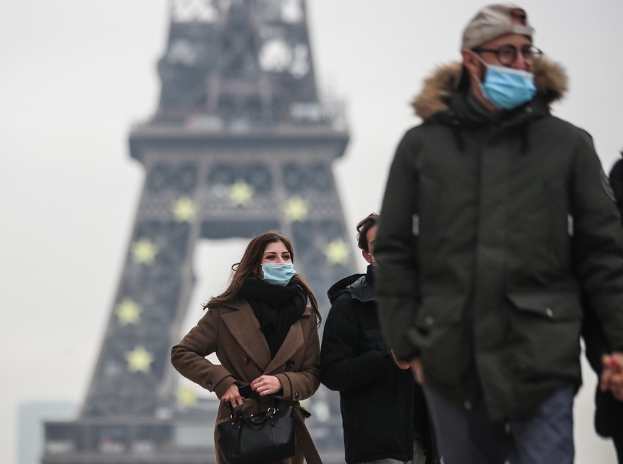 epa09680488 Pedestrians wearing face masks walk near the Eiffel Tower in Paris, France, 12 January 2022. COVID-19 cases have recorded its highest number daily since the start of the pandemic in France ...