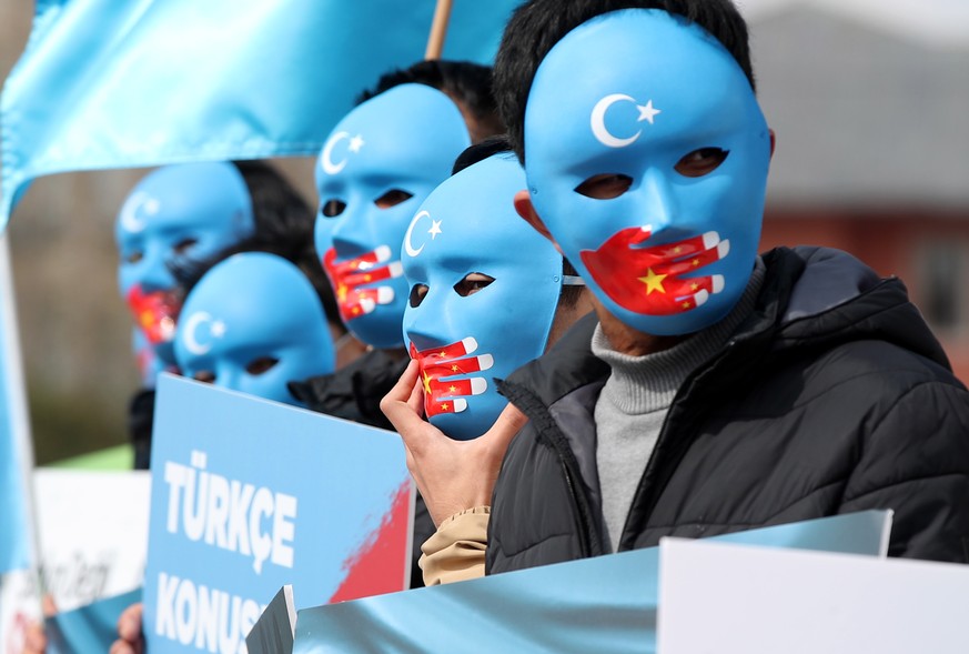 epaselect epa09110126 Uyghur protesters who have not heard from their families living in East Turkestan hold Uyghur flags and placards reading on &#039;it is not a joke, it is a genocide&#039; during  ...
