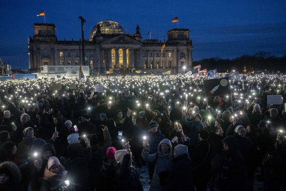People hold up their cell phones as they protest against the AfD party and right-wing extremism in front of the Reichstag building in Berlin, Germany, Sunday, Jan. 21, 2024. (AP Photo/Ebrahim Noroozi)