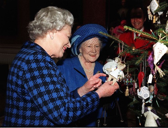 LONDON - DECEMBER 15: Queen Elizabeth II and Queen Elizabeth, The Queen Mother admire Christmas decorations on the Christmas tree in the Picture Gallery at Buckingham Palace after meeting representati ...
