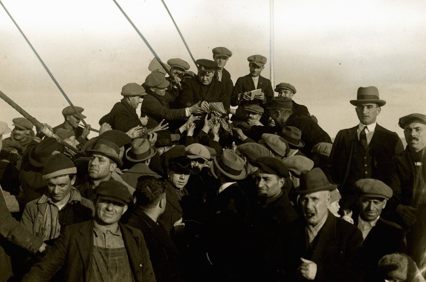 Group of emigrants around the chaplain on the foredeck of the Conte Verde Group of emigrants around the chaplain on the foredeck of the Conte Verde.