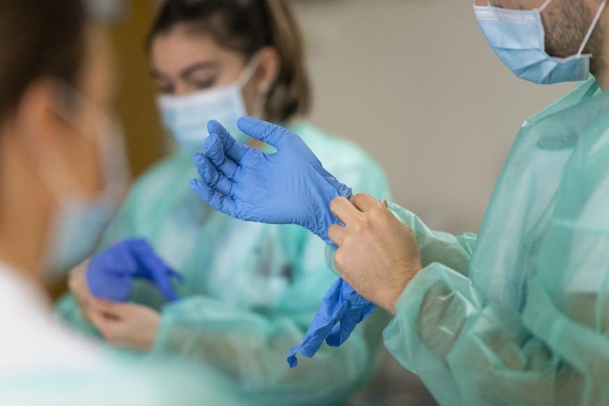 Pflegende ziehen sich vor einem Patientenbesuch Schutzhandschuhe an, auf der Abteilung fuer COVID-Patienten im HFR Freiburg Kantonsspital, am Donnerstag, 26. November 2020 in Fribourg. (KEYSTONE/Aless ...