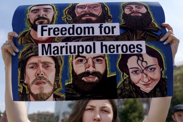 Victoria Dumych, whose husband serves in the Ukrainian military, holds up a sign in support of Ukrainian soldiers from the Azov Regiment who were captured by Russia in May after the fall of Mariupol,  ...