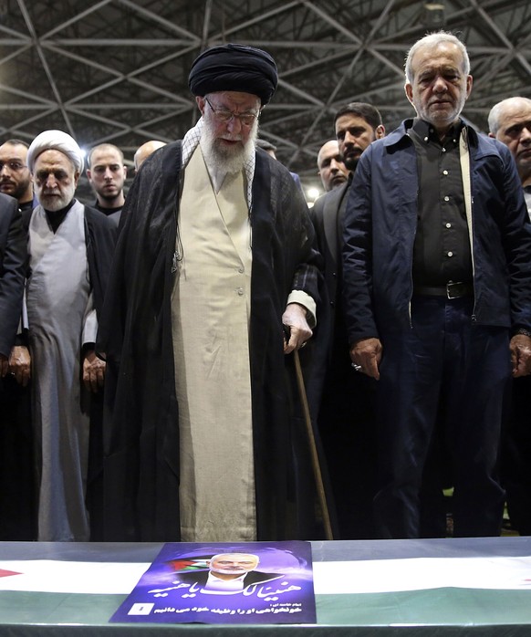 In this photo released by the official website of the office of the Iranian supreme leader, Supreme Leader Ayatollah Ali Khamenei, center, leads a prayer over the coffin of Hamas leader Ismail Haniyeh ...
