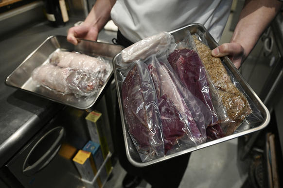 This photo taken on December 9, 2025 shows chef Kiyoshi Fujimoto holding trays of bear meat as he prepares to cook it at his restaurant in Sapporo, in Japan’s northern Hokkaido prefecture.