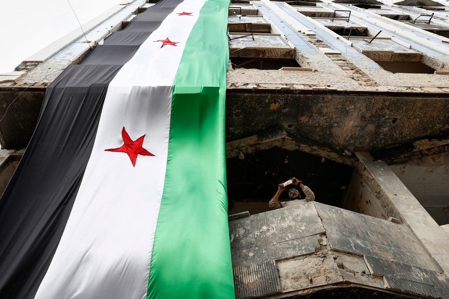 A man takes a picture with his mobile phone as people gather to commemorate the seventh anniversary of the chemical attack for the first time after the fall of the Assad government in the town of Doum ...