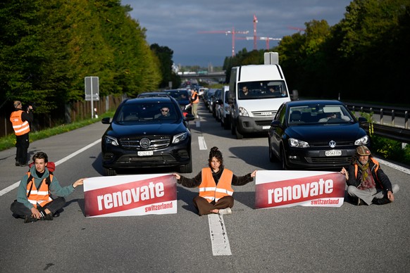 Environmental activists members of Renovate Switzerland sit down in the road during a roadblock action of the A1 motorway, in Lausanne, Switzerland, Tuesday, October 4, 2022.(KEYSTONE/Laurent Gilliero ...