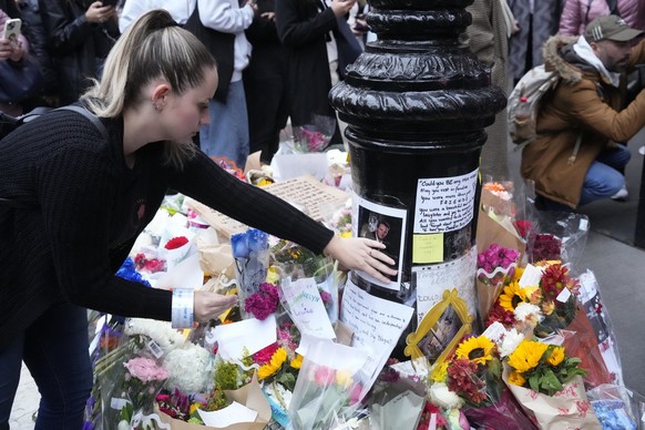 People gather by a makeshift memorial for Matthew Perry outside the building shown in exterior shots of the television show &quot;Friends&quot; on Monday, Oct. 30, 2023, in New York. Perry, who played ...