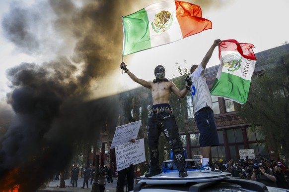 epaselect epa12165673 Activists hold aloft Mexican flags as cars burn during protests sparked by immigration raids in Los Angeles, California, USA, 08 June 2025. US President Donald Trump has deployed ...