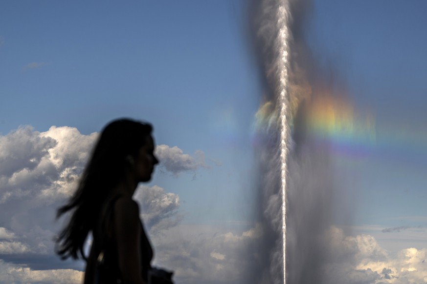 epa10219787 A person passes in front of a rainbow caused by the famous water fountain &#039;Le Jet d&#039;Eau&#039; in Geneva, Switzerland, 02 October 2022. EPA/MARTIAL TREZZINI