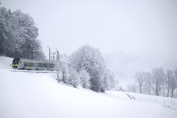 Ein Regionalzug dser BLS faehrt durch die Schneelandschaft, am Samstag, 2. Dezember 2023, in Uetendorf. Ein Tiefdruckgebiet beschert Schnee bis in die Niederungen. (KEYSTONE/Peter Schneider)