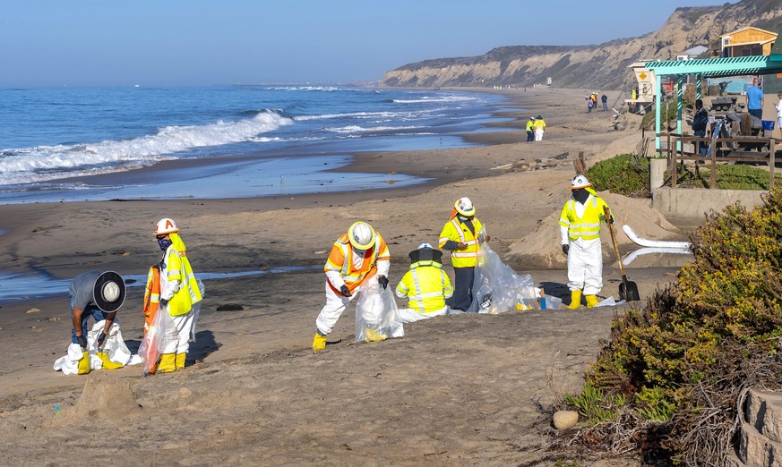 Shoreline cleanup crews pick up tar balls that have washed ashore along the beach at Crystal Cove State Park in Laguna Beach, Calif., Thursday, Oct. 14, 2021. Shoreline cleanup crews continue to pick ...