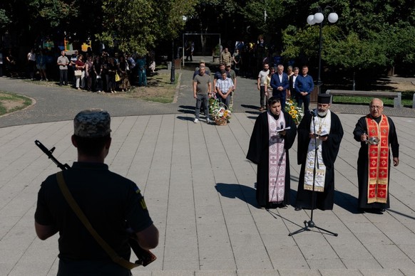 (FILES) This photograph taken on August 28, 2026 shows military personnel standing to attention as orthodox priests take part in a commemorative event ahead of the Day of Remembrance for the Defenders ...
