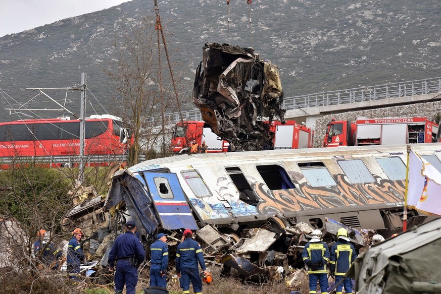 epa10497121 Crane vehicles try to remove pieces of damaged train wagons after a collision near Larissa city, Greece, 01 March 2023. Fire fighter and ambulance service crews remain at the scene, while  ...