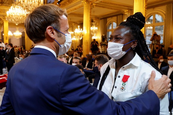 epa09466136 French President Emmanuel Macron (L) awards French judoka Clarisse Agbegnenou with the French Legion of Honour during a ceremony in honour of French medallists of the Tokyo 2021 Olympic an ...
