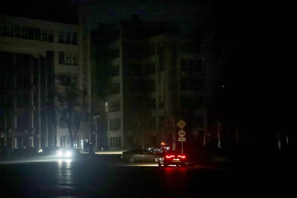 Des voitures circulent dans une rue près du bâtiment Derzhprom, plongée dans l&#039;obscurité totale à Kharkiv, en Ukraine, le 8 novembre 2025.