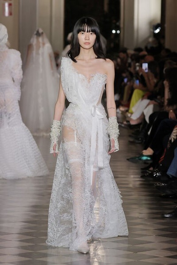 Le drapé asymétrique et les gants incrustés de perles apportent une touche rebelle à la tradition nuptiale, tandis que le tissu léger et fluide lui permet de danser toute la nuit.