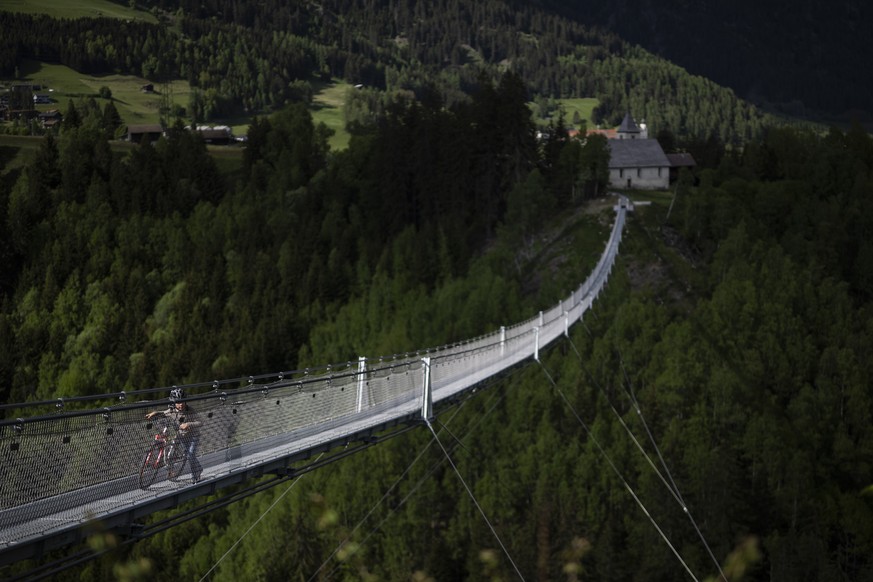 KEYPIX - Ein Junge schiebt sein Fahrrad ueber La Pendenta, die mit 280 Metern laengste Haengebruecke Graubuendens, am Mittwoch, 14. Mai 2025, in Disentis. (KEYSTONE/Gian Ehrenzeller)