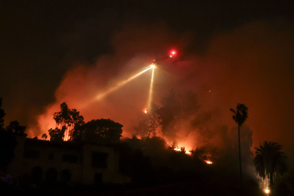 Un hélicoptère lutte contre les flammes. En raison des vents violents, les décollages ne sont possibles que par intermittence.