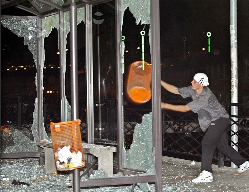 A demonstrator smashes a rubbish bin through a bus station window in cenral Geneva late on Sunday 01 June 2003, while groups of demonstrators clashed with police overnight and caused damages to shops ...