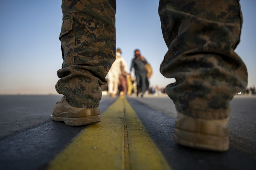 In this image provided by the U.S. Air Force, a U.S. Marine provides security for evacuees boarding a U.S. Air Force C-17 Globemaster III at Hamid Karzai International Airport in Kabul, Afghanistan, T ...